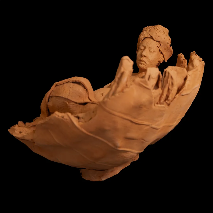 amai, low view of the red stoneware vessel, the figure's head and shoulders raised at one end