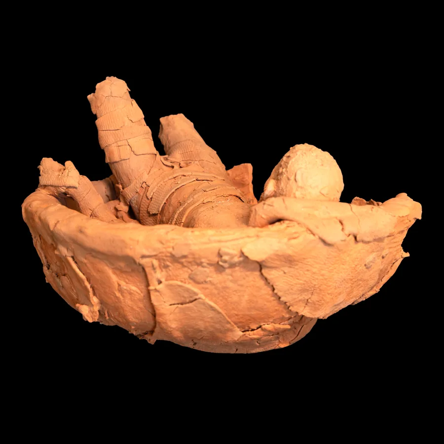 arkard, red stoneware bowl with a reclining figure inside, seen from the end where the legs are missing
