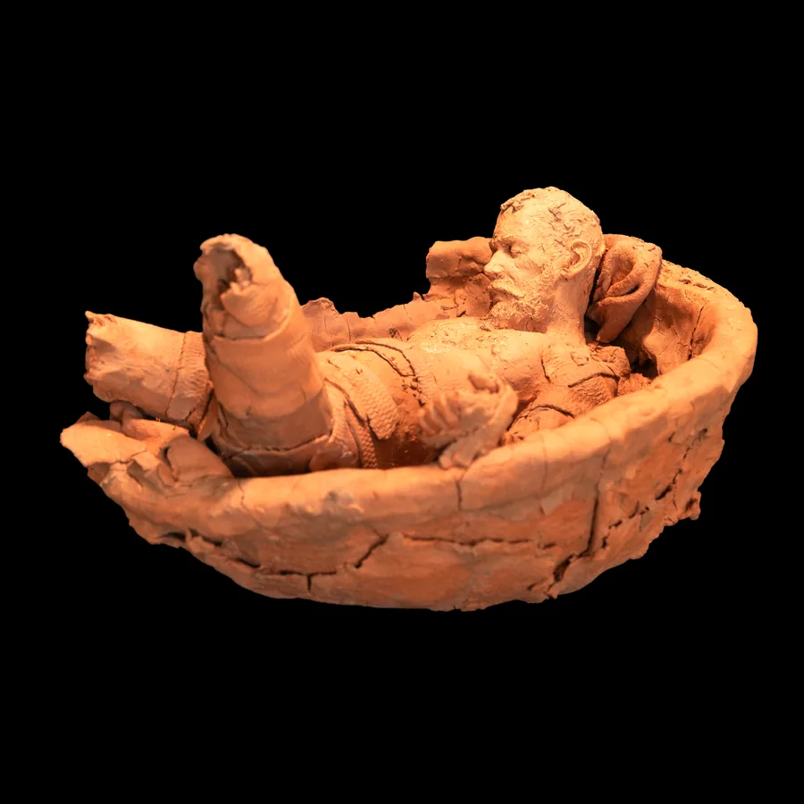 arkard, a bearded male figure lying in a red stoneware bowl, one arm raised