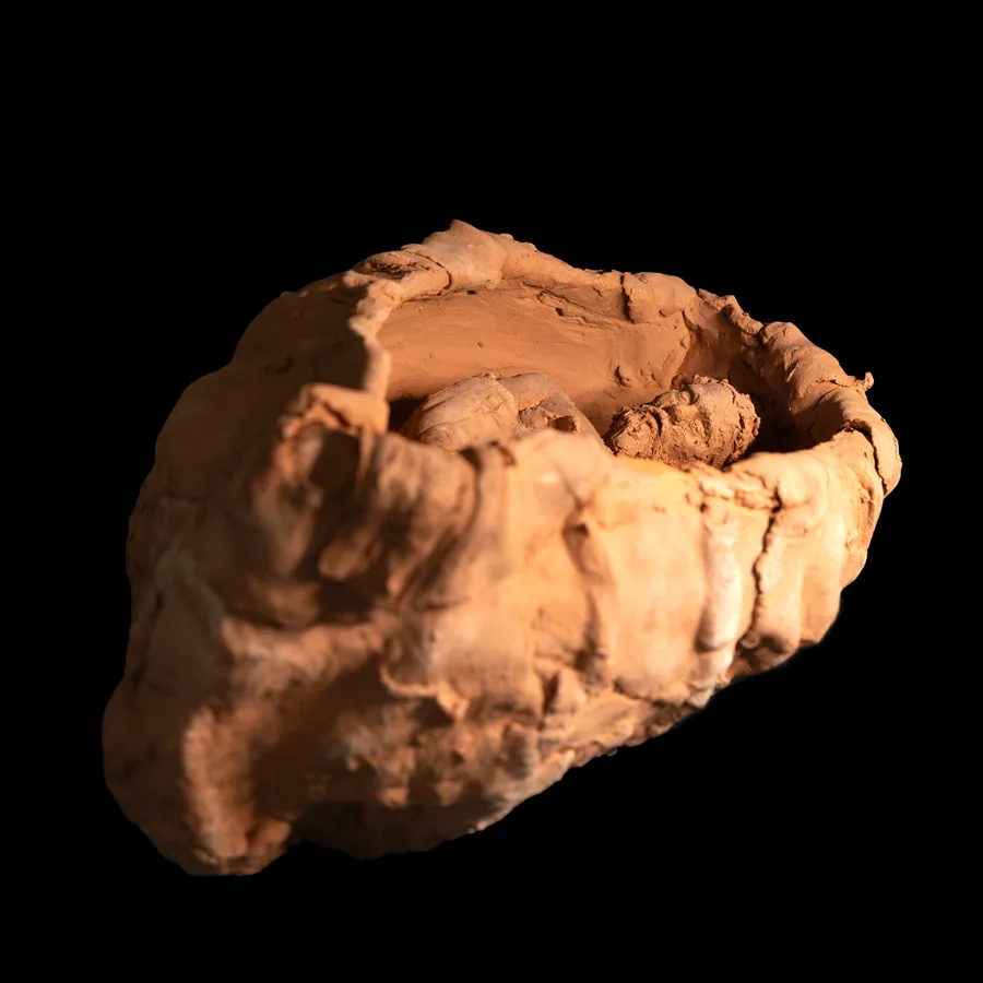 blith, terracotta vessel with a small figure lying low in its hollow, seen from above
