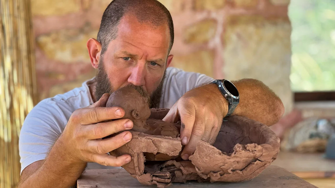 renzo brandsma at work on arkard, leaning over the bowl and shaping the figure